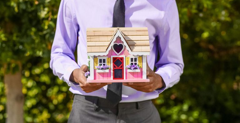 An estate agent holding the model of a house which begs the question - Can estate agents ask for proof of funds?